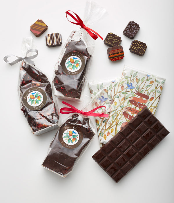 Artisan handmade chocolate bars and boxed pieces wrapped with red ribbon on a white background.