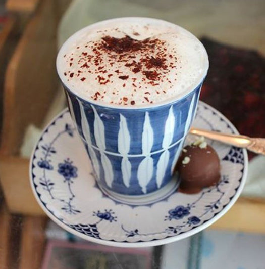 Artisan handmade chocolate in a blue and white ceramic cup, topped with cocoa speckles.
