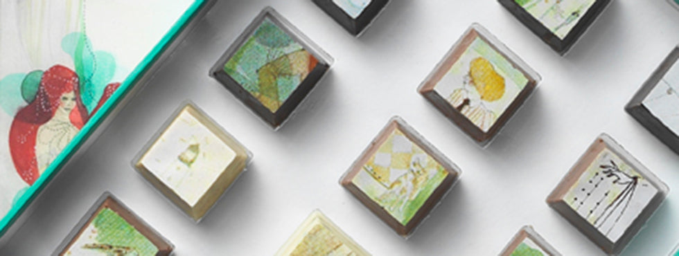 artisan handmade framed illustrated cards on a white tabletop, with green and gold tones.